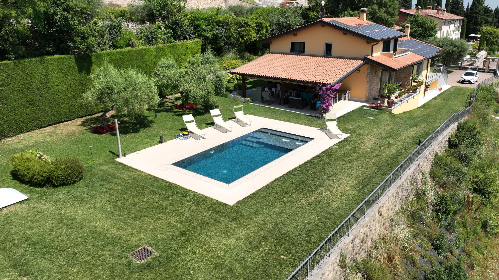 Piscina a Sfioro rettangolare con spiaggia interna in testa, doppio blower idromassaggio e scalinata laterale, rivestimento nero effetto marmorizzato