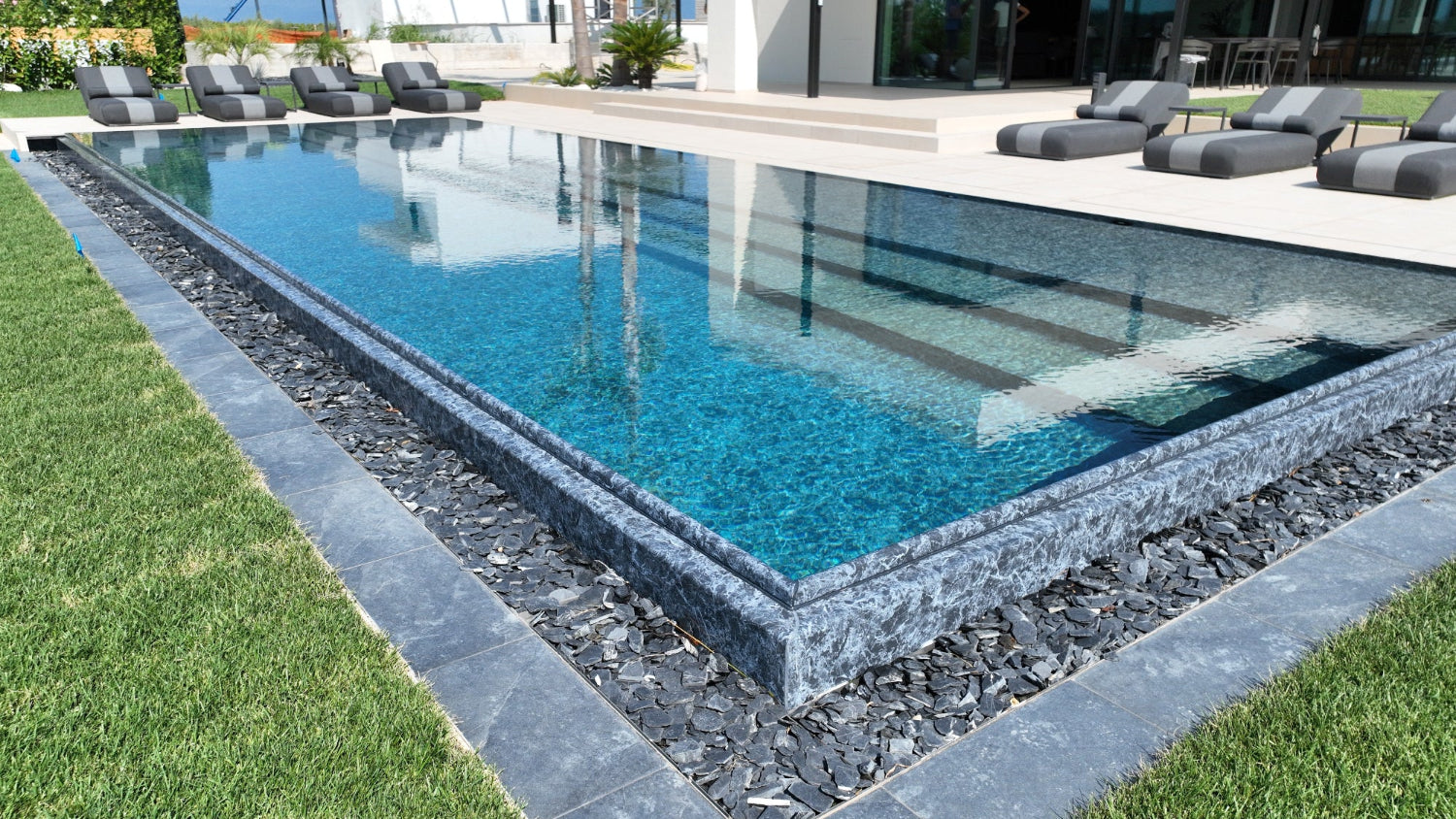 Piscina a sfioro Lazise con effetto cascata nero marmorizzato spiaggia a tutta lunghezza Lago di Garda design lusso