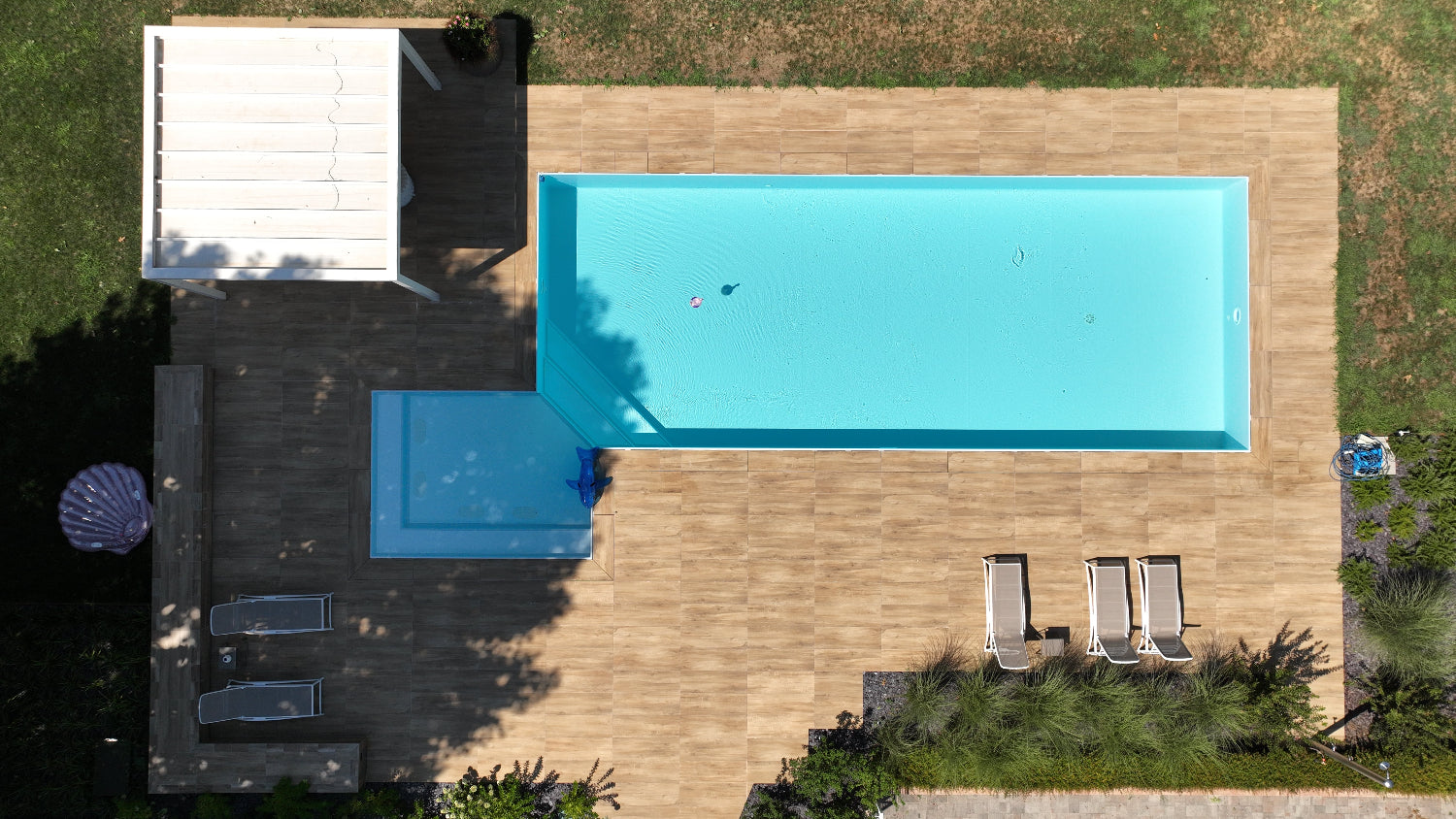 Piscina a sfioro Zavatti realizzata a Cittadella rivestimento chiaro spiaggia angolare esterna