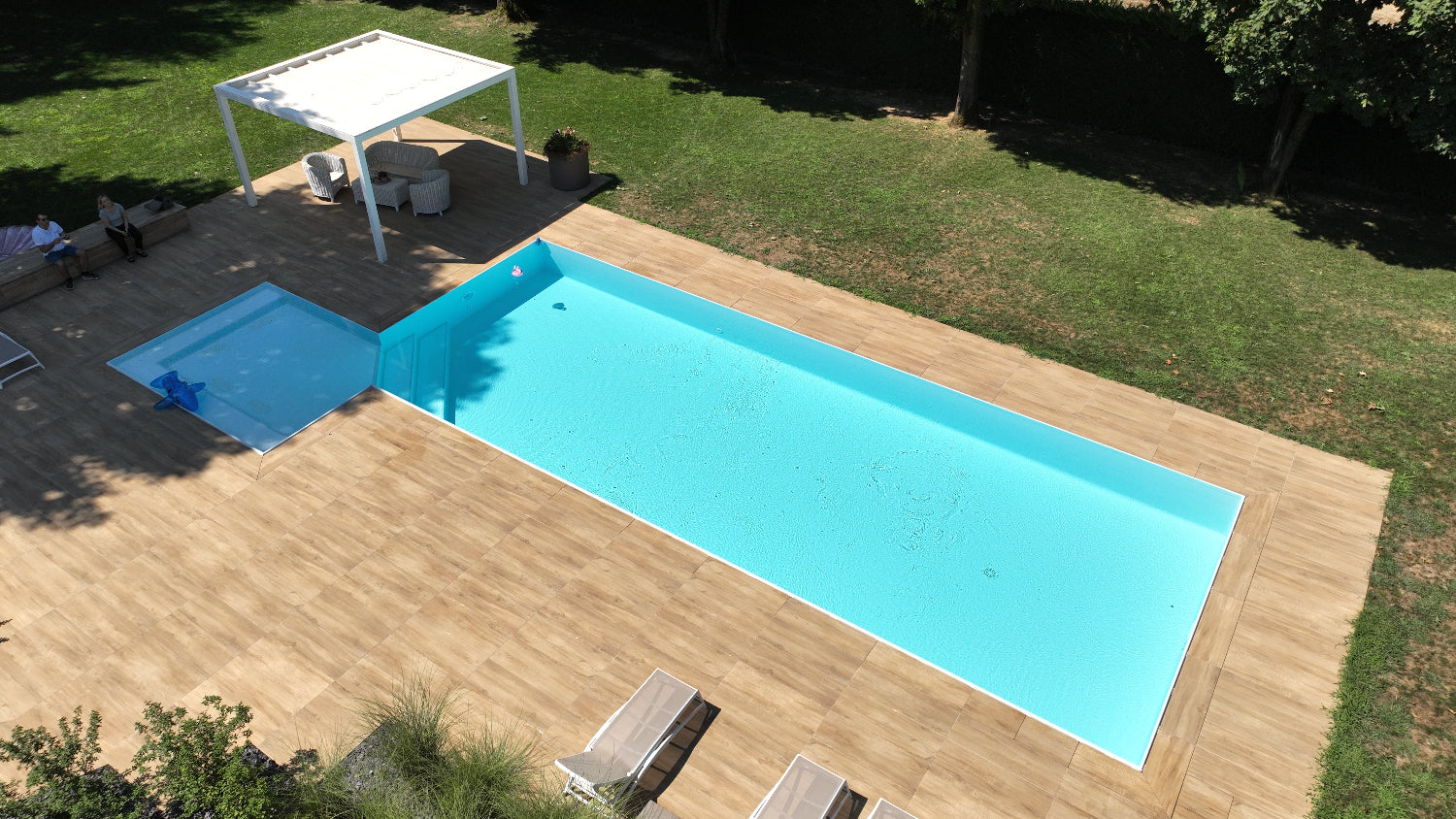 Piscina a sfioro Zavatti realizzata a Cittadella rivestimento chiaro spiaggia angolare esterna con idromassaggio