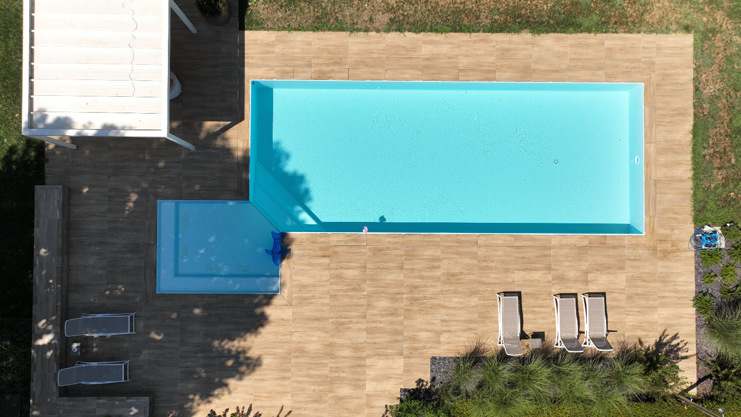 Piscina a sfioro Zavatti realizzata a Cittadella rivestimento chiaro spiaggia angolare esterna con idromassaggio zona relax