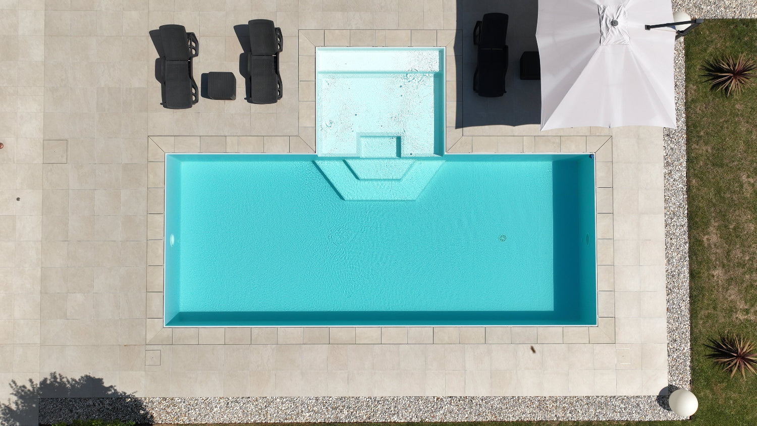 Piscina a sfioro con rivestimento chiaro, realizzata a San Biagio di Callalta, Treviso con spiaggia centrale