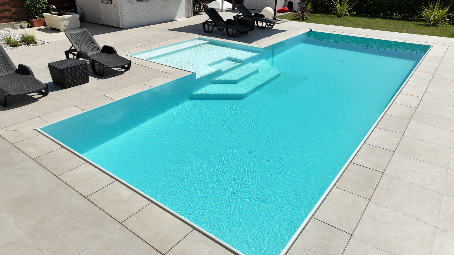 Piscina a sfioro con rivestimento chiaro, realizzata a San Biagio di Callalta, Treviso con spiaggia centrale esterna