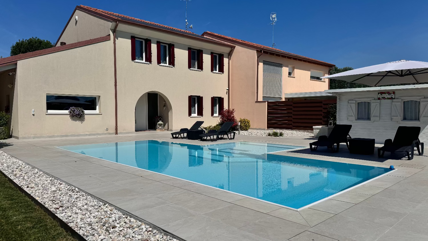 Piscina a sfioro con rivestimento grigio chiaro e spiaggia bianca