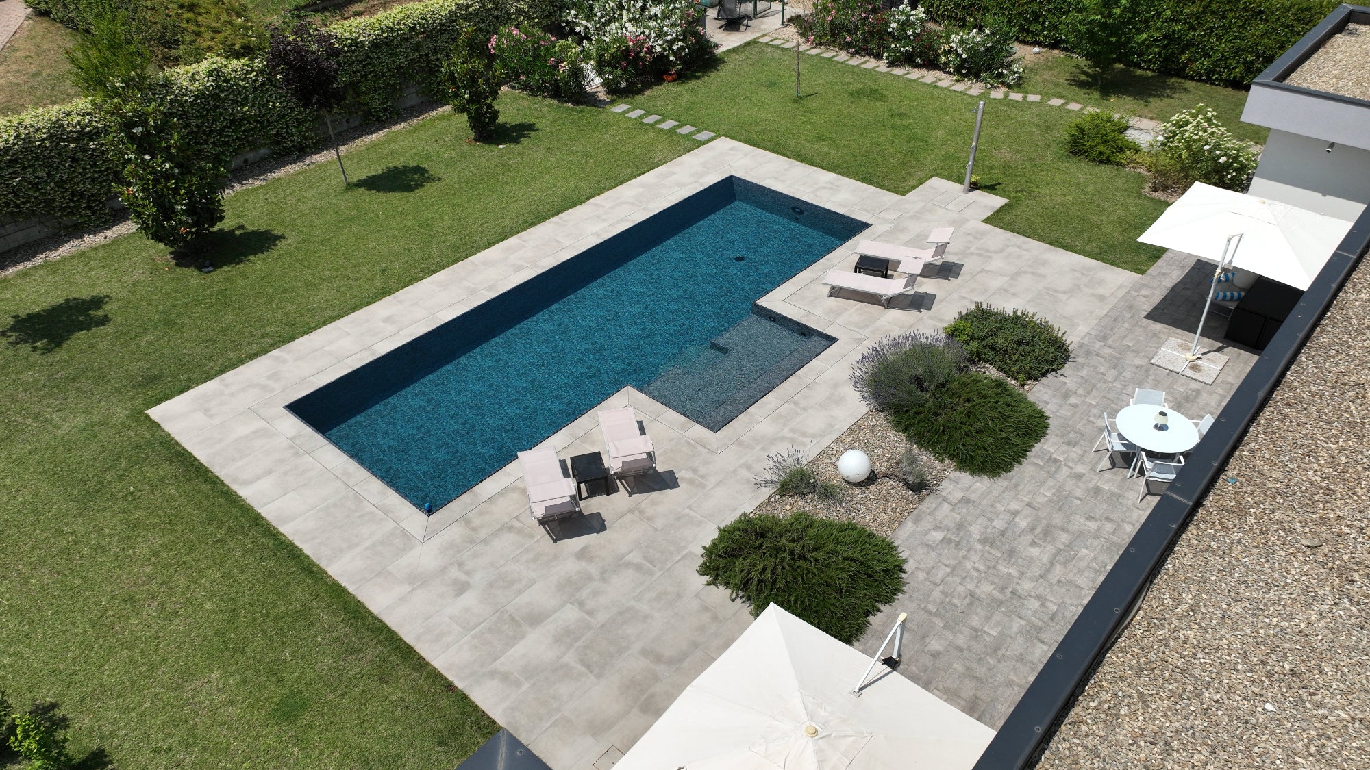 Piscina a sfioro rettangolare con bagnasciuga centrale e rivestimento nero effetto marmorizzato, senza vasca di compenso tecnologia esclusiva Zavatti Piscine