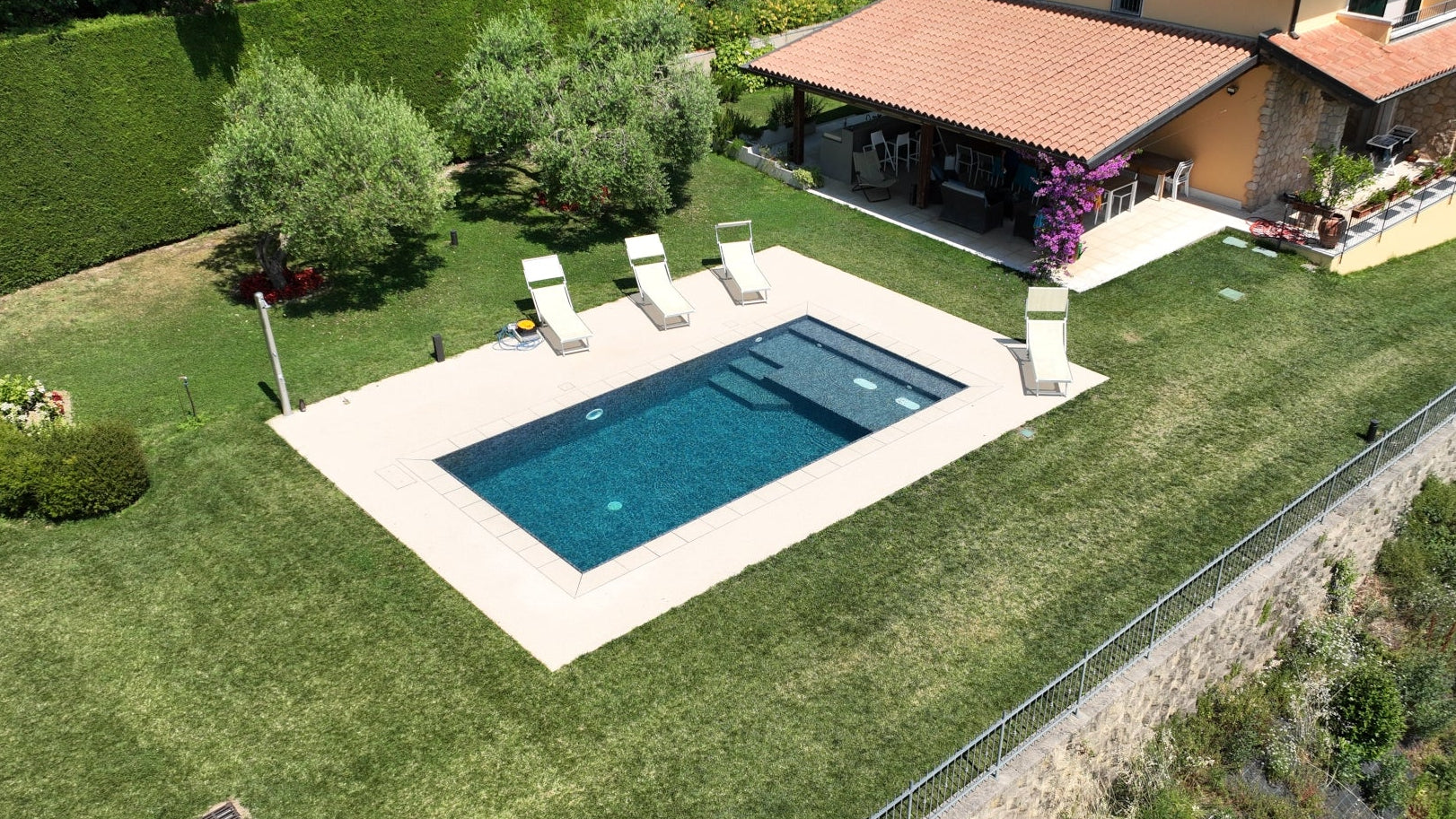 Piscina a sfioro rettangolare con zona relax interna tutta larghezza con idromassaggio e rivestimento nero effetto marmo a Cavaion Veronese (VR)