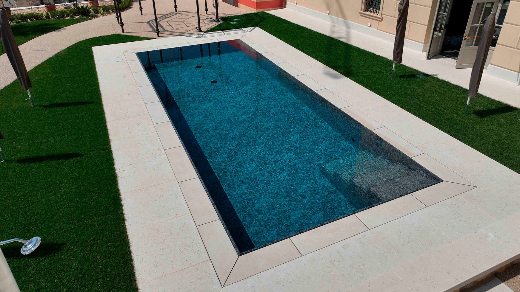 Piscina rettangolare nera marmorizzata costruita da Zavatti piscine a Sfioro senza vasca di compenso.