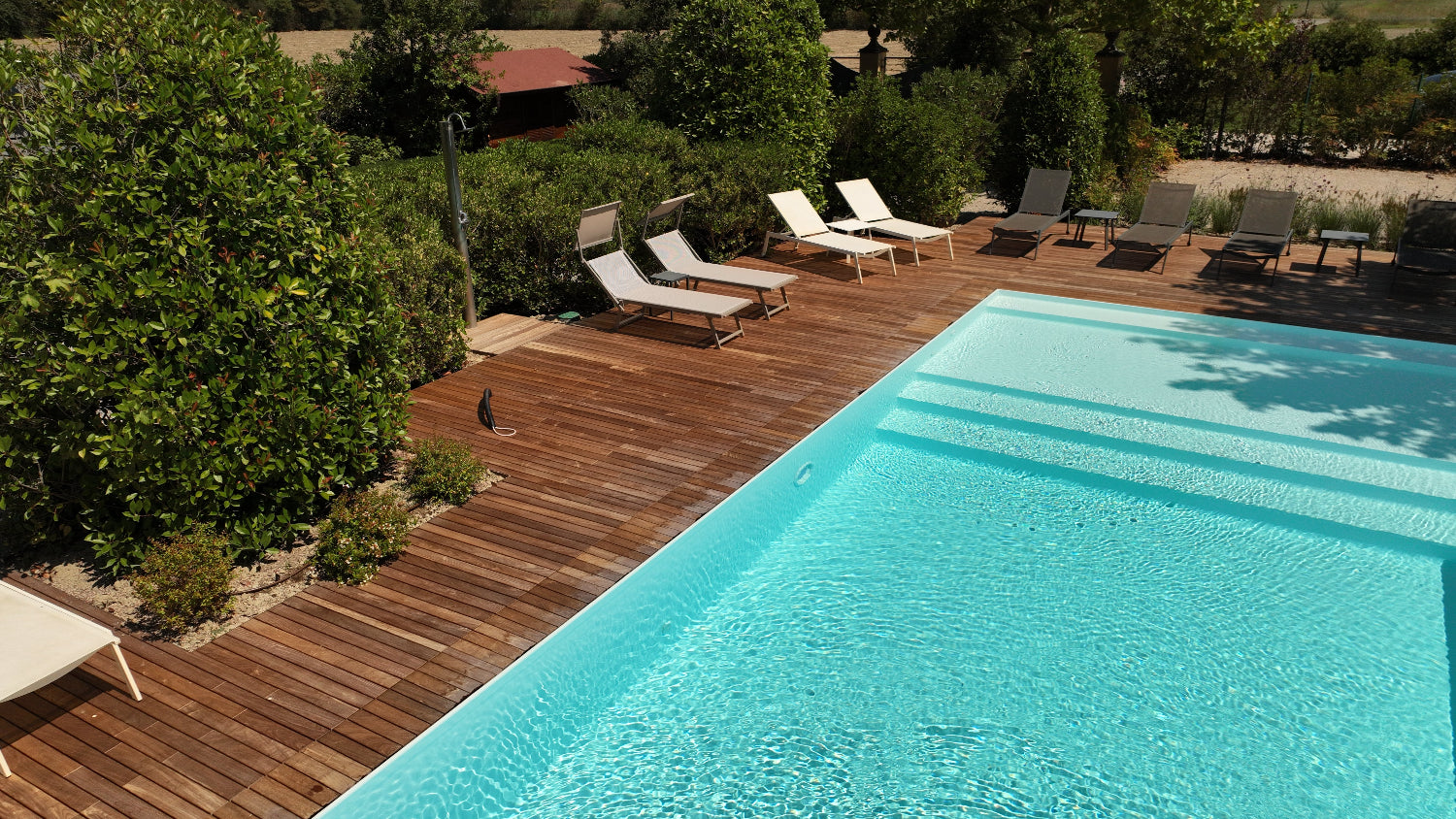 Piscina a sfioro rettangolare realizzata a Modena con rivestimento bianco, spiaggia in testa