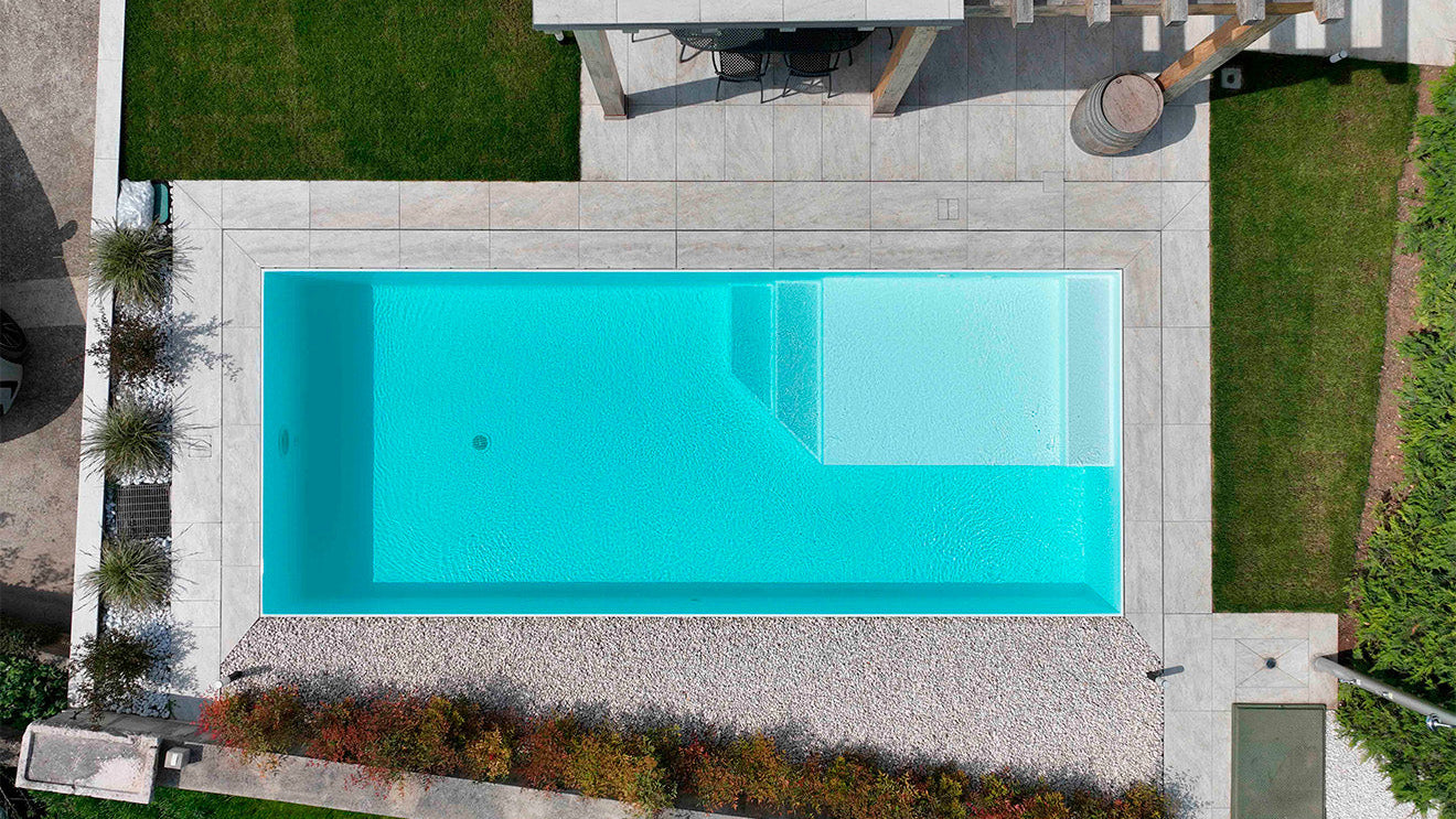 Piscina a sfioro senza vasca di compenso color bianco dal design pulito e moderno con spiaggia interna