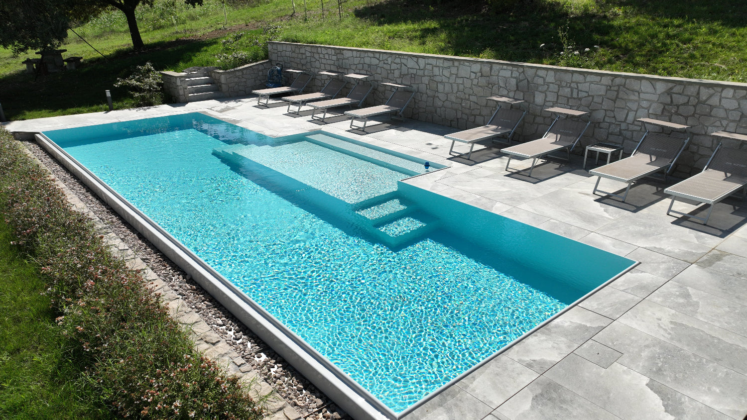 Piscina a sfioro senza vasca di compenso con sassi decorativi