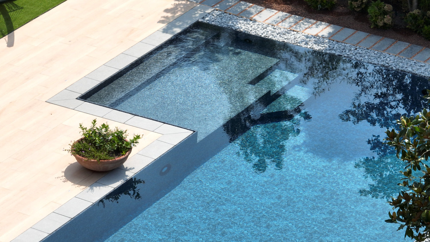 Piscina a sfioro senza vasca di compenso con spiaggia esterna a L
