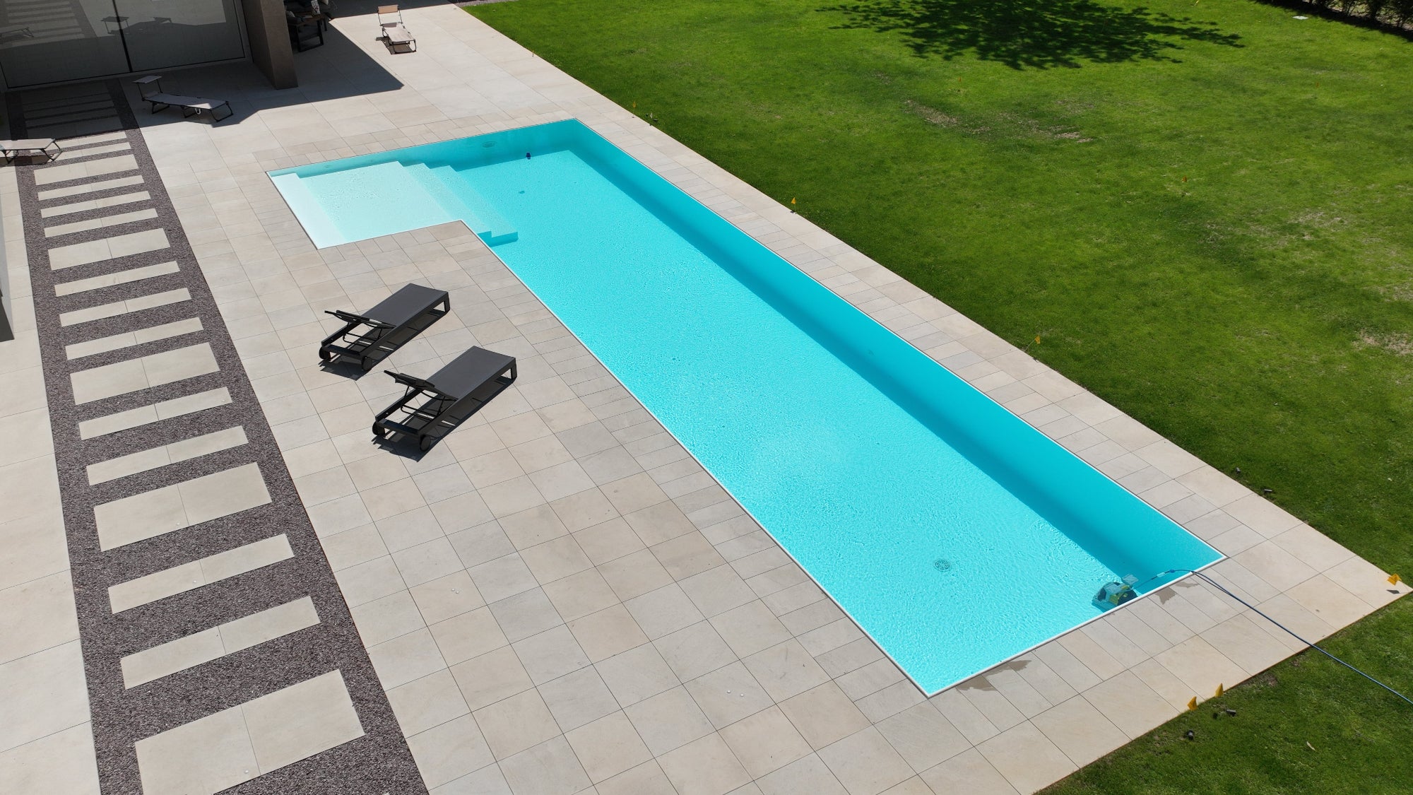 Piscina a sfioro senza vasca di compenso con spiaggia esterna ad elle dal design moderno, rivestimento bianco 
