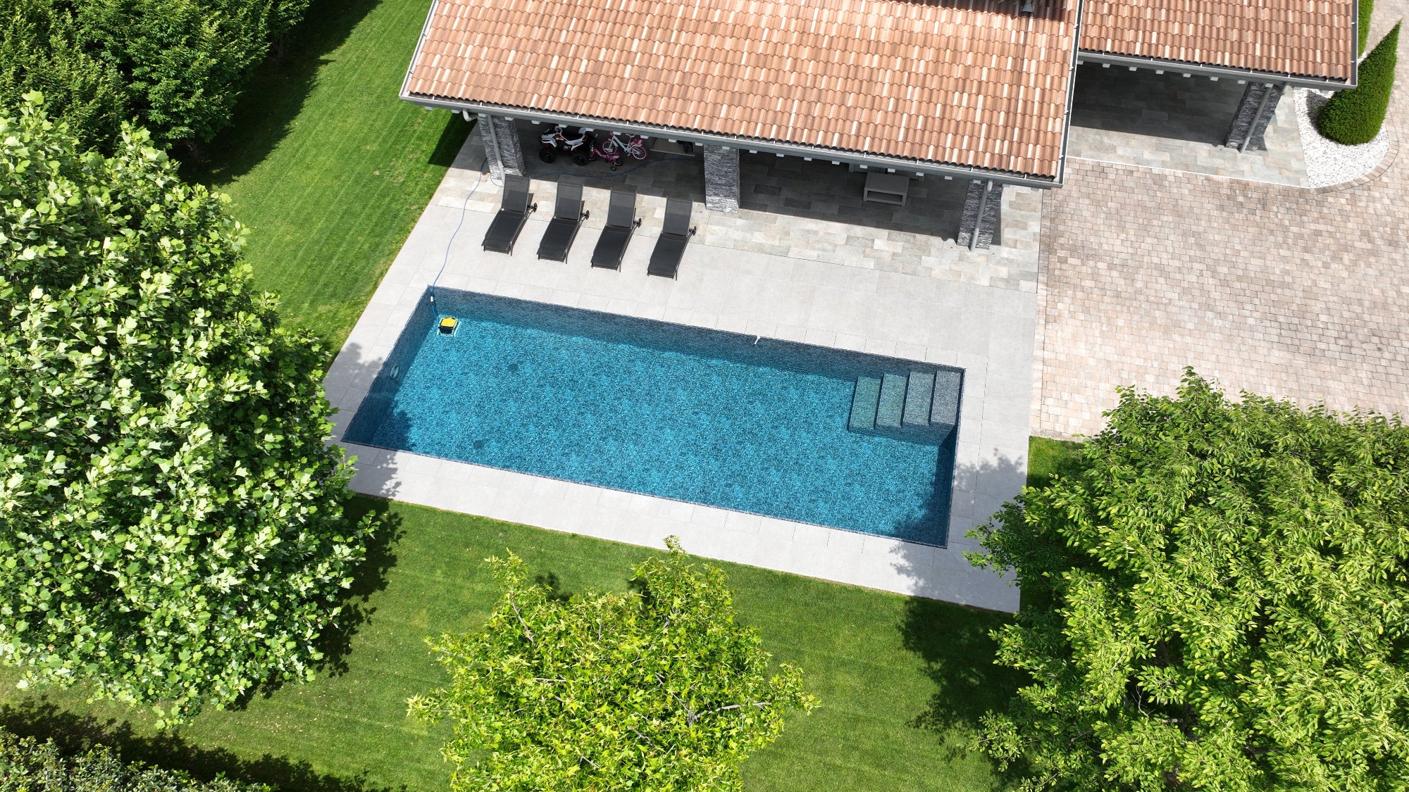 Piscina a sfioro senza vasca di compenso rettangolare con scala interna e rivestimento nero marmorizzato a Cittadella (PD)