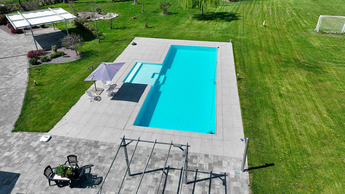 piscina a sfioro senza vasca di compenso con spiaggia esterna centrale e rivestimento bianco a Marzaglia