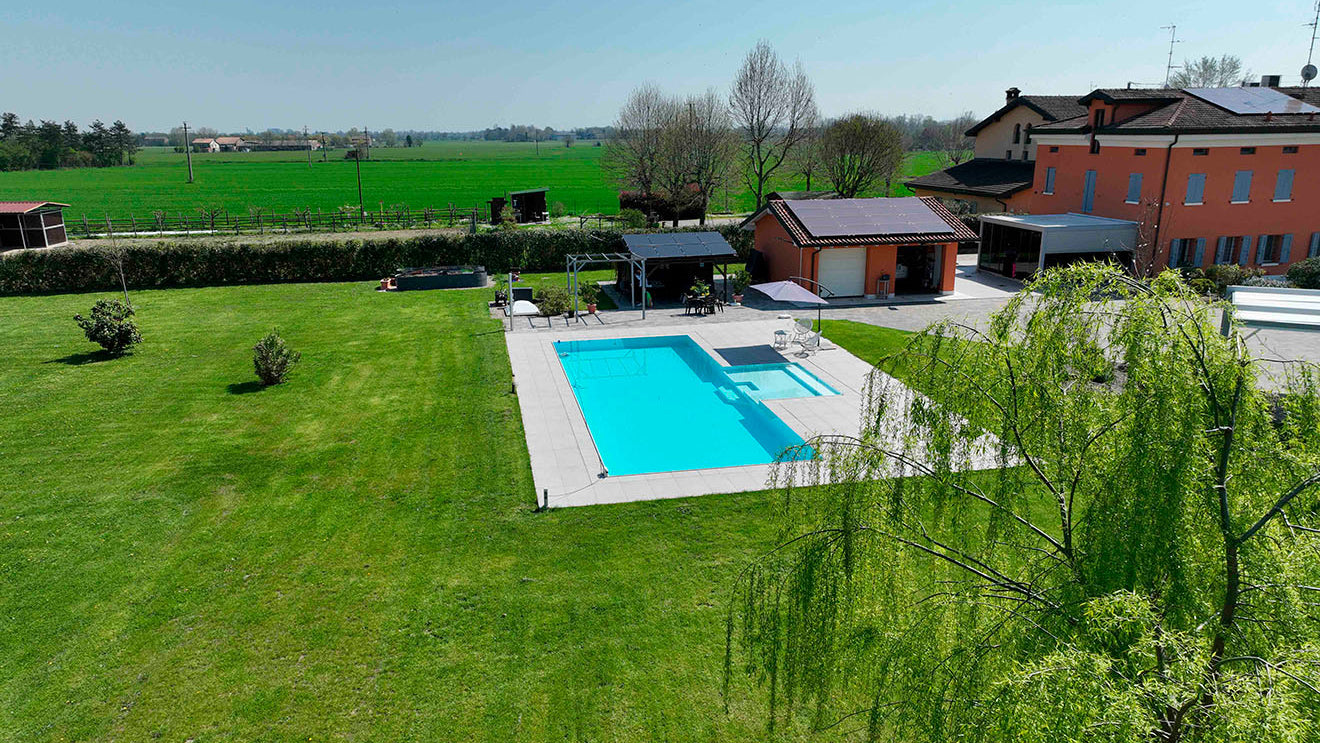 Piscina sfioro con zona relax centrale e rivestimento bicolore bianco e grigio chiaro a Marzaglia