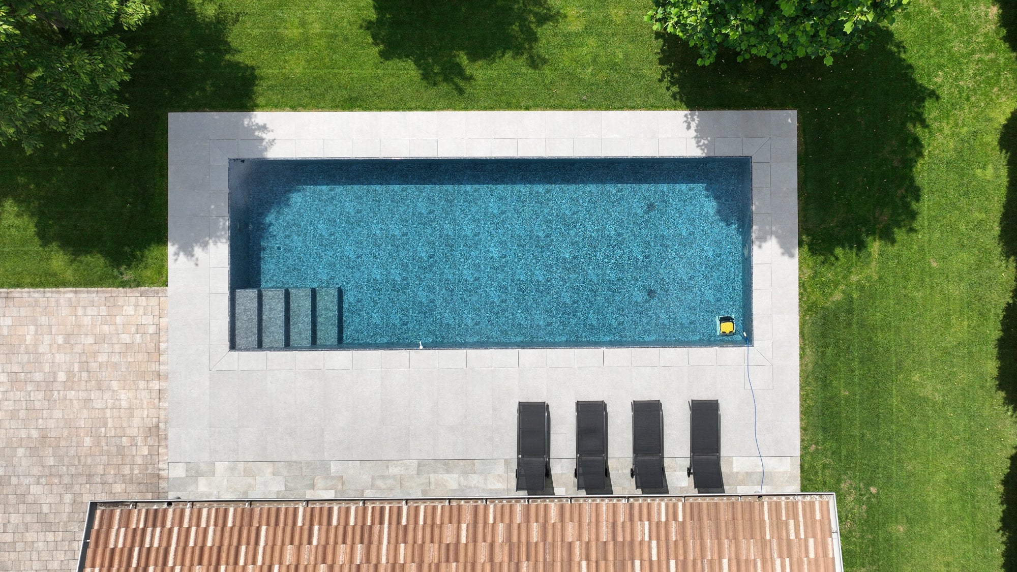 piscina a sfioro senza vasca di compenso a Cittadella (PD), forma classica rettangolare con gradini interni e rivestimento nero marmorizzato.