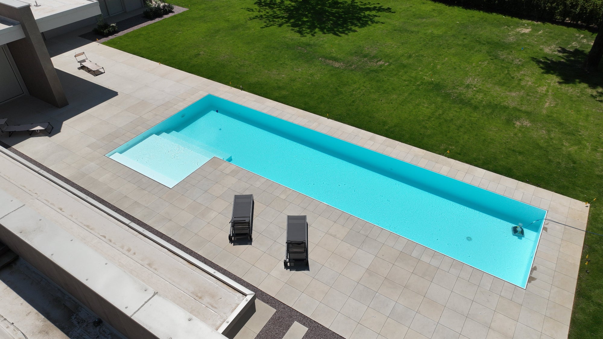 Piscina sfioro rettangolare con spiaggia esterna ad elle, rivestimento bianco senza vasca di compenso, esclusiva Zavatti