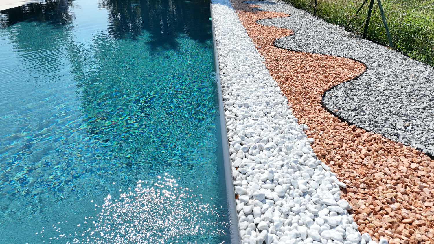 piscina a sfioro grigia con sassi decorativi