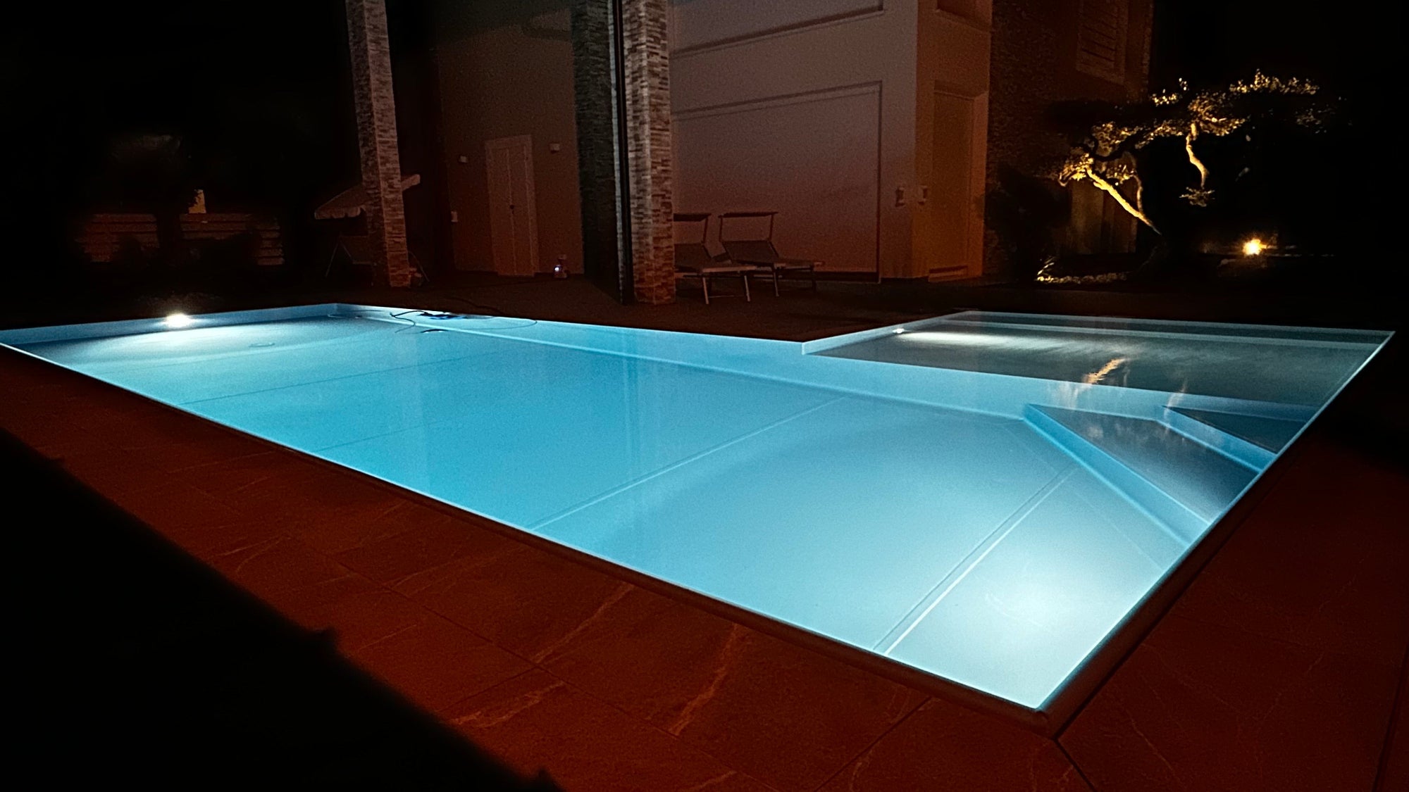 piscina a sfioro illuminata di sera
