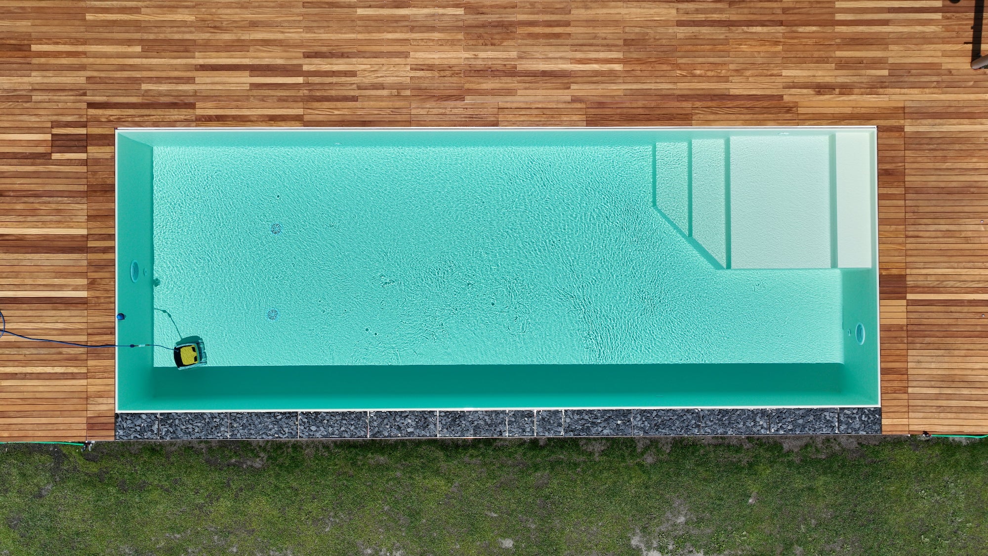 piscina a sfioro rettangolare con spiaggia interna angolare e color sabbia, vaschette con sassi decorativi su lato lungo - zona Pavullo nel Frignano