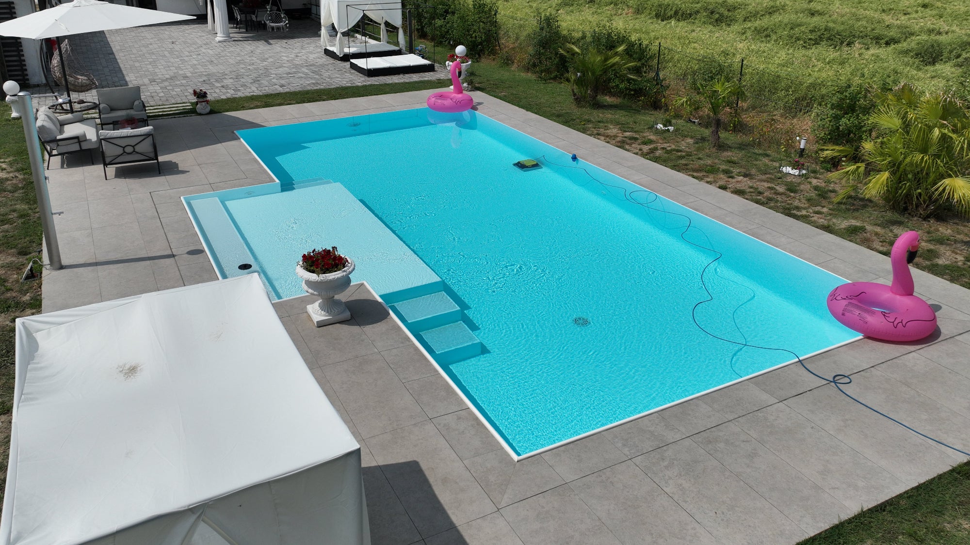 piscina a sfioro rivestita in pvc armato bianco e gradini grigio chiaro, spiaggia centrale semiesterna a San Giovanni in Persiceto