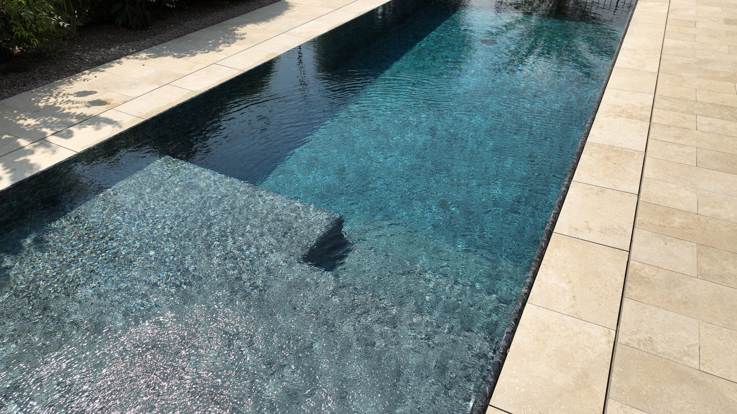 piscina a sfioro senza vasca di compenso con spiaggia interna in testa nero marmorizzato