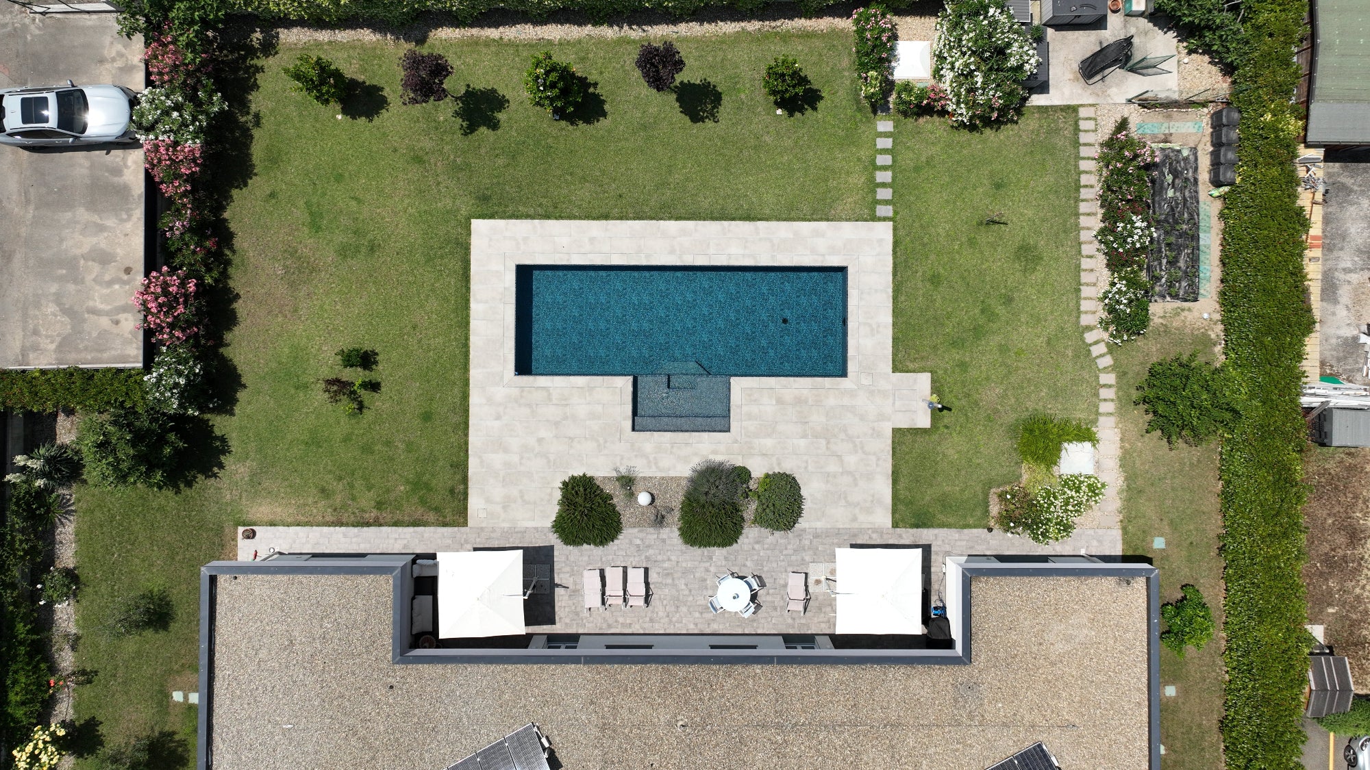 piscina a sfioro senza vasca di compenso con zona relax esterna centrale e rivestimento nero marmorizzato Reggio Emilia, tecnologia Zavatti