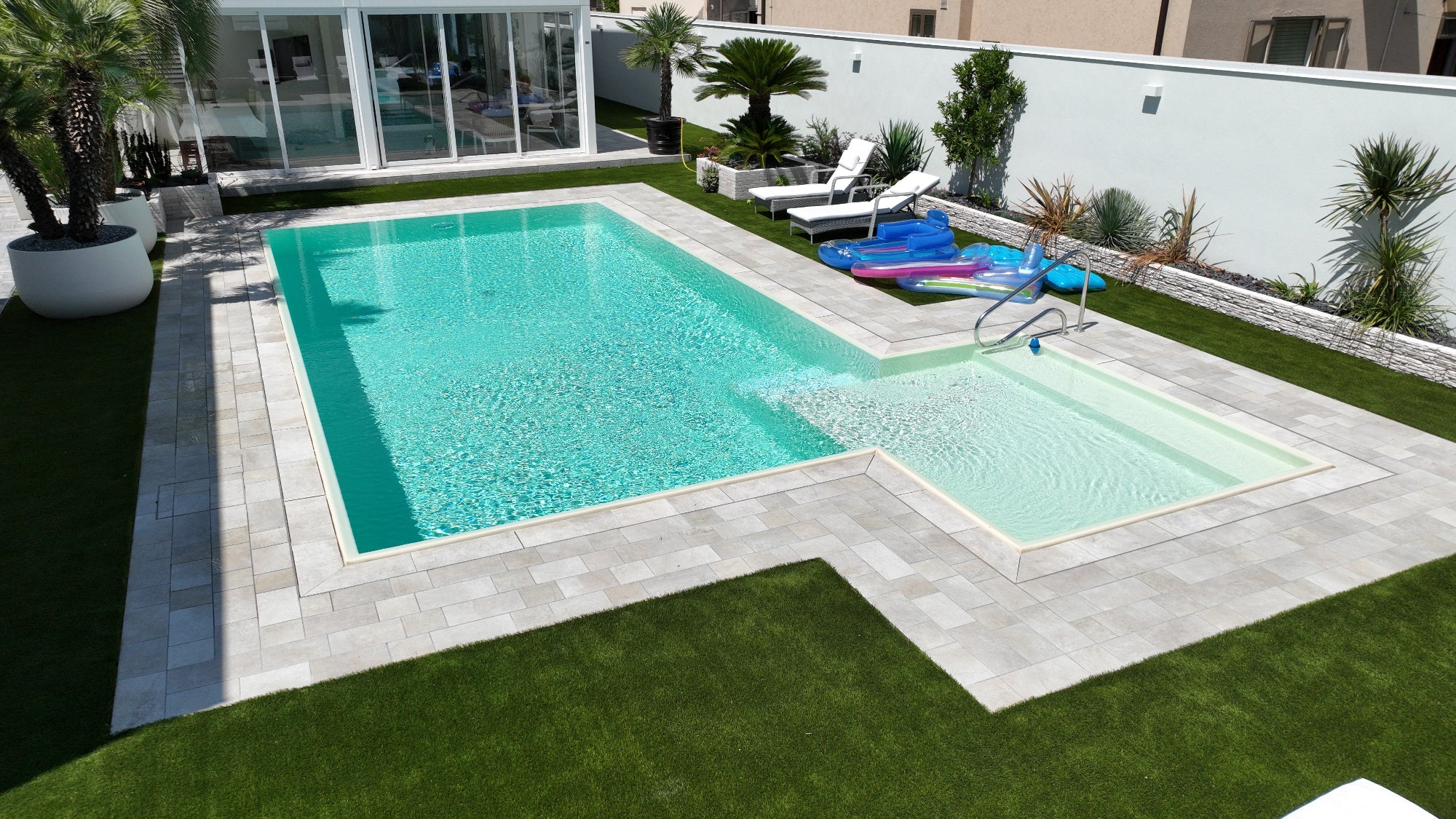 piscina realizzata a Cento da Zavatti Piscine rivestimento color sabbia con bagnasciuga angolare esterno