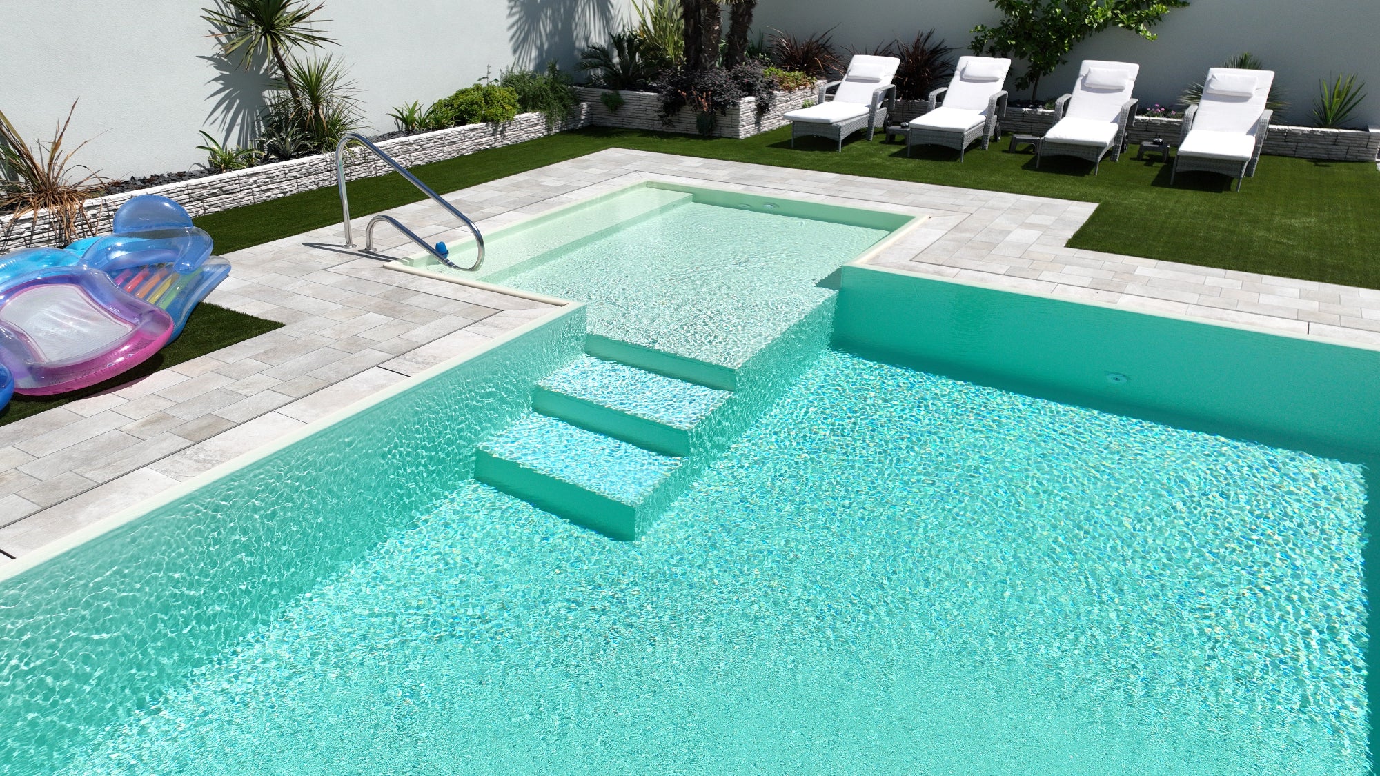 piscina realizzata a Cento da Zavatti Piscine rivestimento color sabbia con bagnasciuga angolare esterno con scala per ingresso