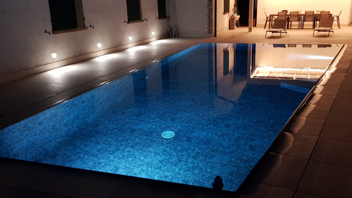 piscina realizzata a Mantova da Zavatti Piscine con forma asimmetrica illuminata di sera
