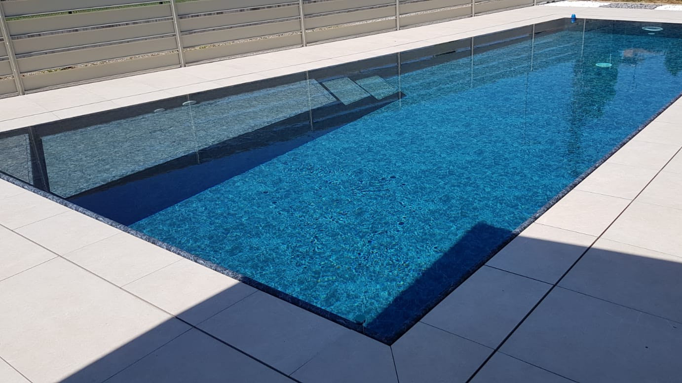 piscina realizzata a Mantova da Zavatti Piscine con forma asimmetrica rivestimento nero marmorizzato