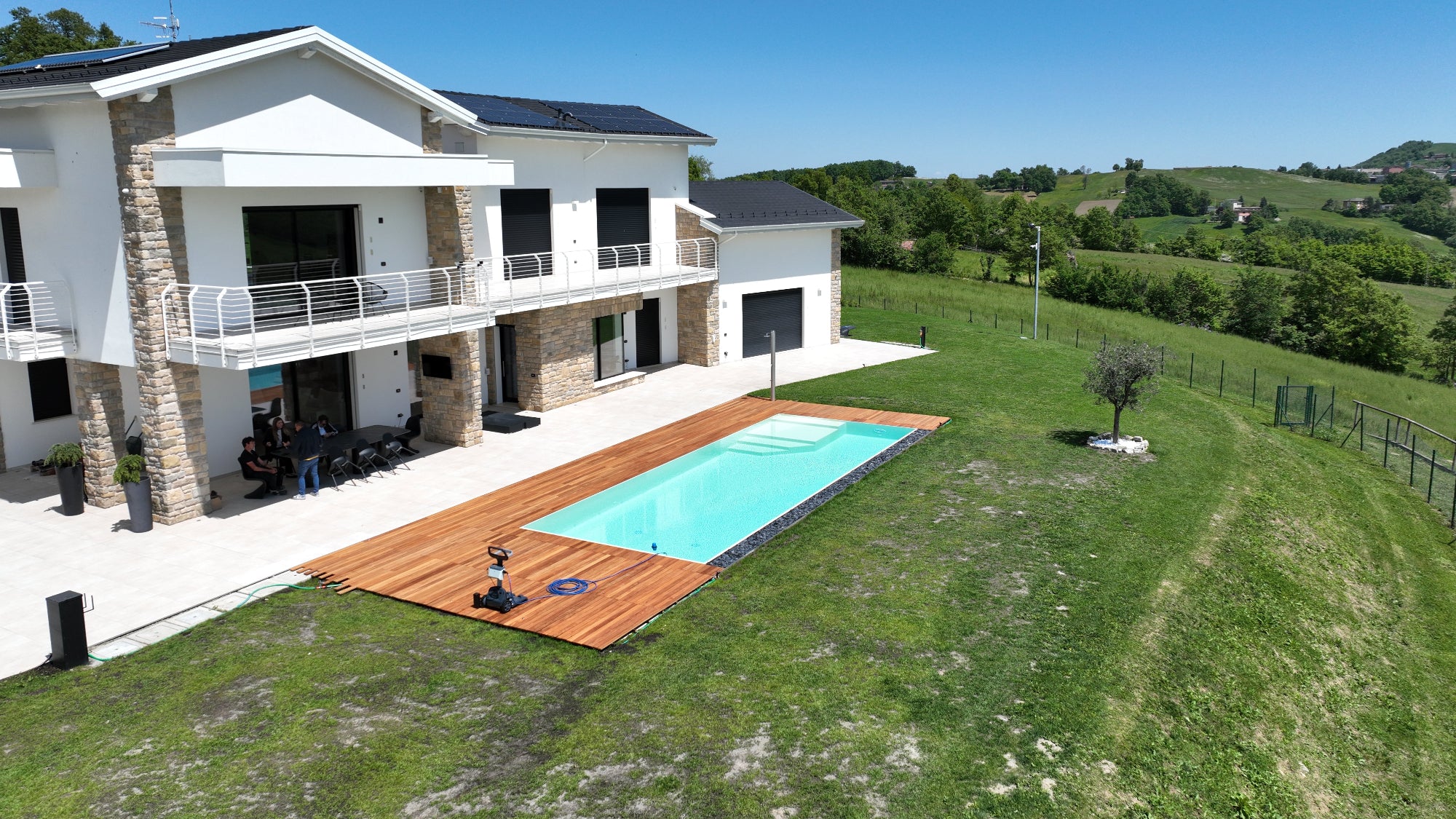piscina rettangolare a sfioro senza vasca di compenso color sabbia con zona relax interna e pavimento legno a Pavullo nel Frignano
