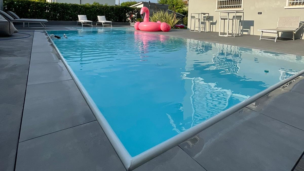 piscina rivestita con colore bianco con spiaggia angolare esterna a Rivalta sul Mincio ristrutturazione dettaglio sfioro