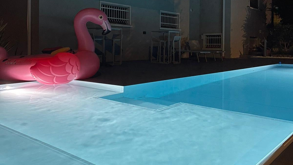 piscina rivestita con colore bianco con spiaggia angolare esterna a Rivalta sul Mincio ristrutturazione dettaglio sfioro di notte