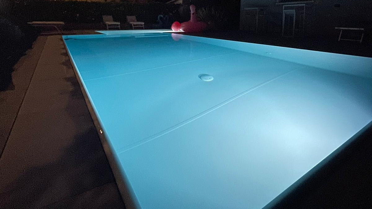 piscina rivestita con colore bianco con spiaggia angolare esterna a Rivalta sul Mincio ristrutturazione dettaglio sfioro di notte illuminata con fari bianchi proiettori