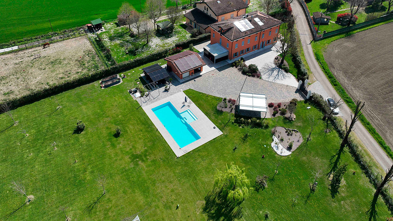 piscina sfioro rettangolare con zona relax esterna centrale immersa nel verde a Marzaglia