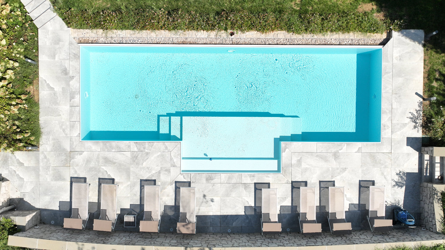 riprese drone piscina a sfioro con spiaggia semi esterna centrale grigio chiaro