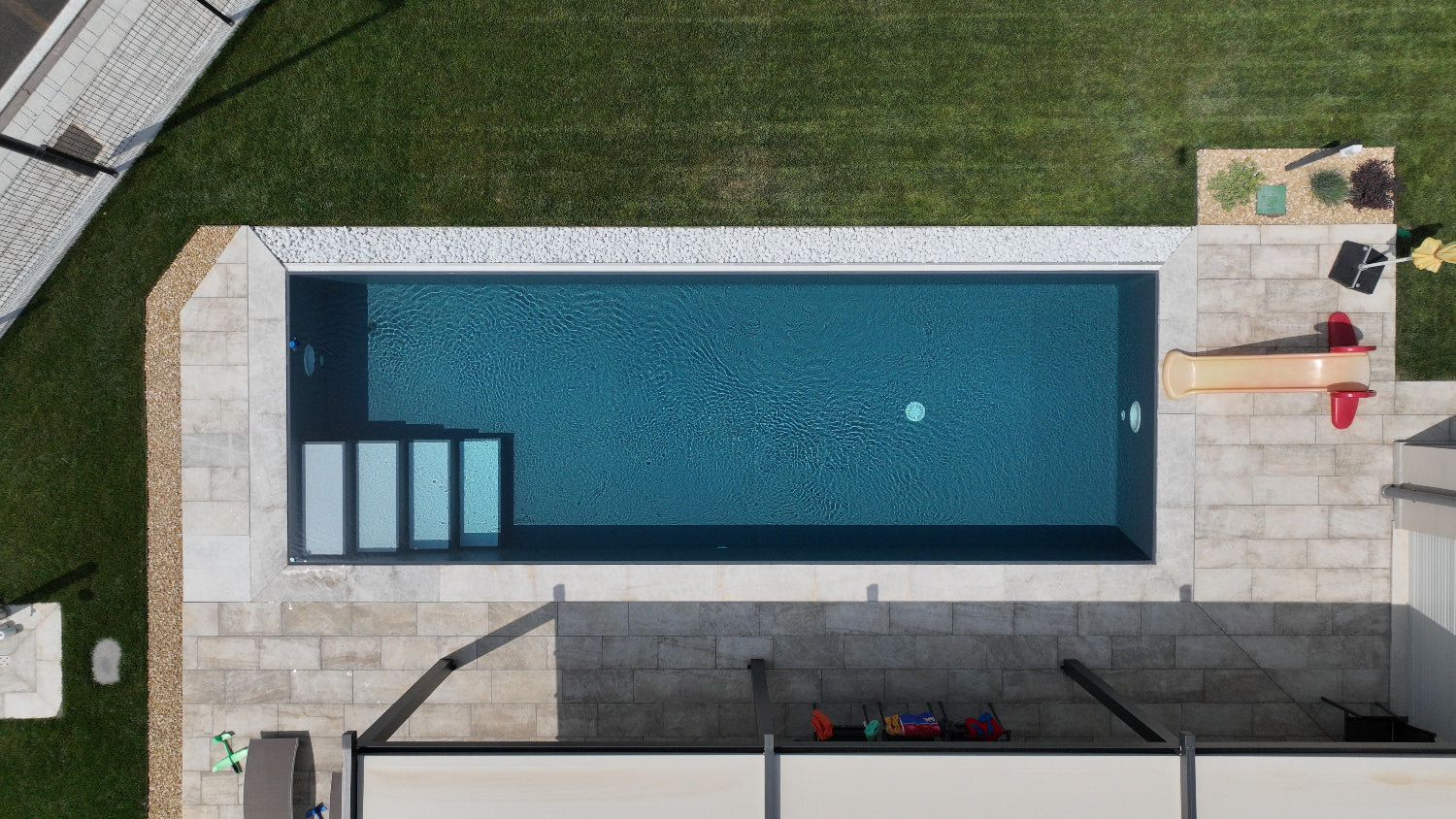 vista drone di piscina a sfioro rivestita con telo grigio scuro e scalini di ingresso