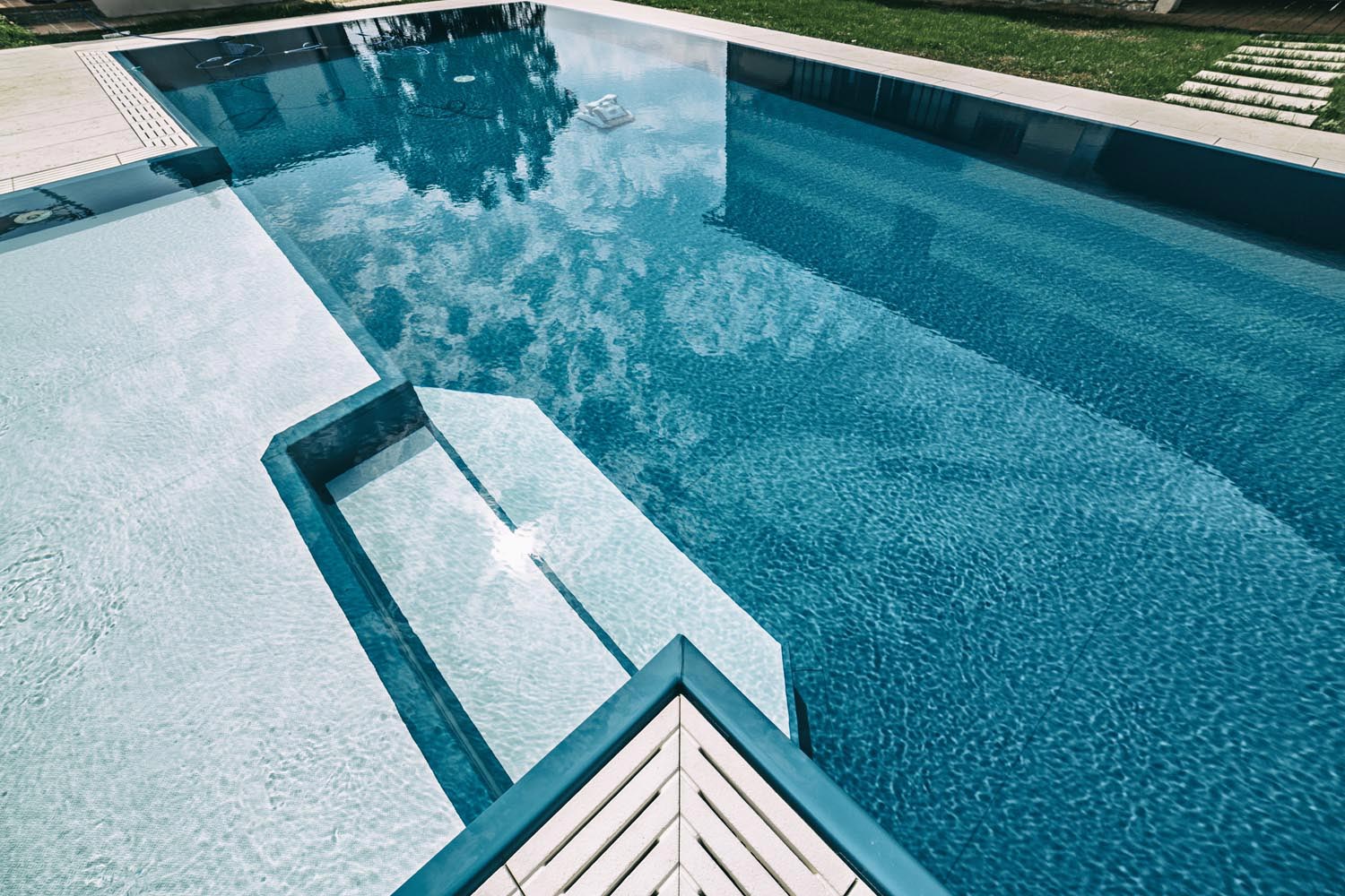 Riflessi di una piscina a sfioro senza vasca di compensazione con liner blu.