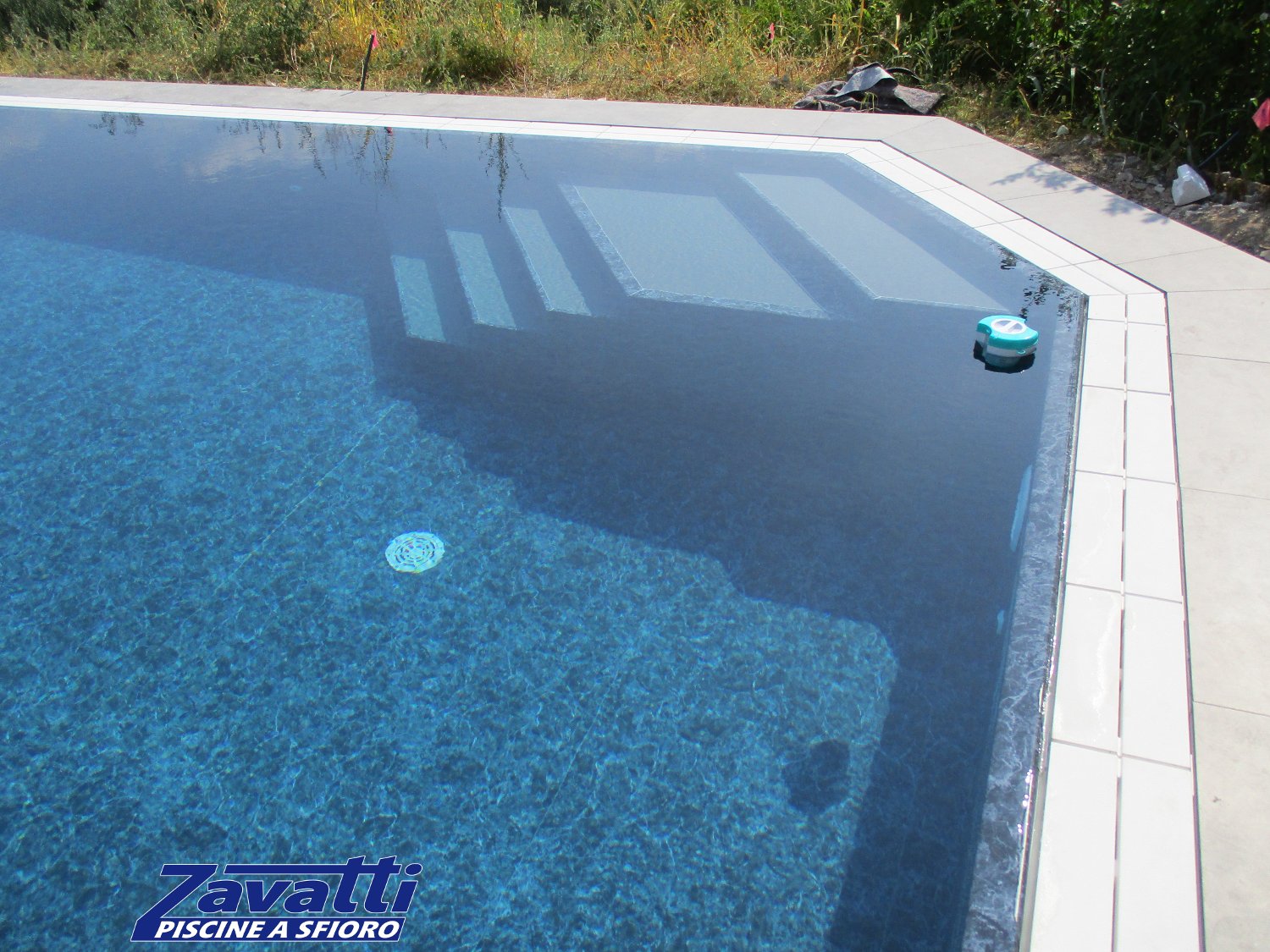 Dettaglio piscina sfioro con rivestimento marmorizzato e scala bicolore interna