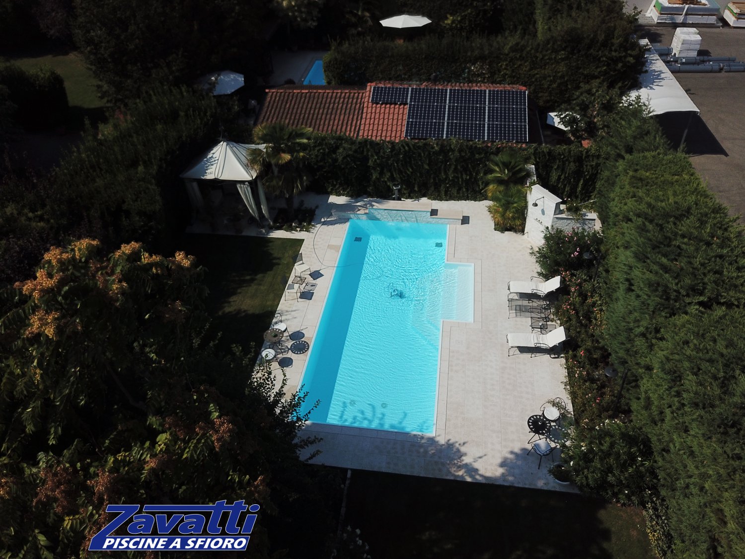 Vista aerea di una piscina a sfioro antisismica e ad altissimo risparmio energetico. Rivestimento bianco e scalinata centrale a gradoni trapezioidali